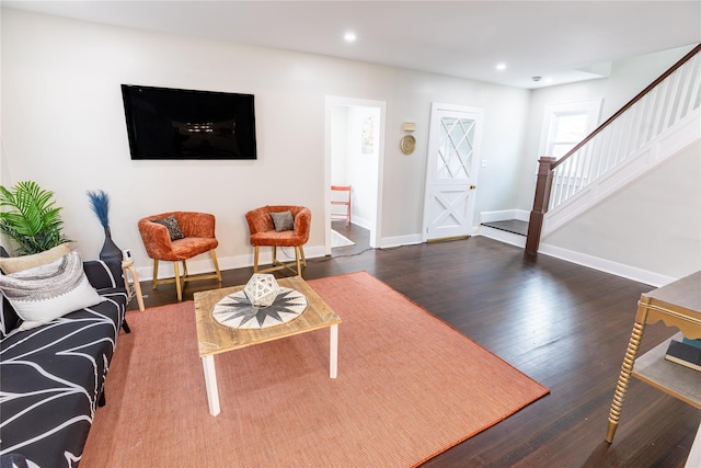 living area with baseboards, wood finished floors, recessed lighting, and stairway