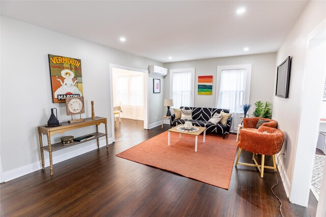 living room featuring an AC wall unit, dark wood-style floors, recessed lighting, and baseboards