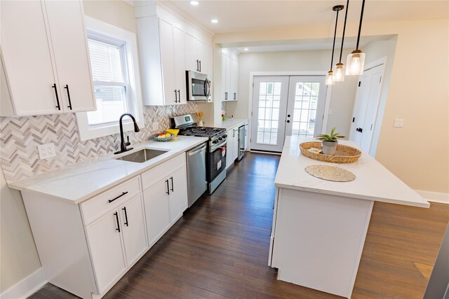 kitchen featuring appliances with stainless steel finishes, a sink, a kitchen island, white cabinets, and recessed lighting