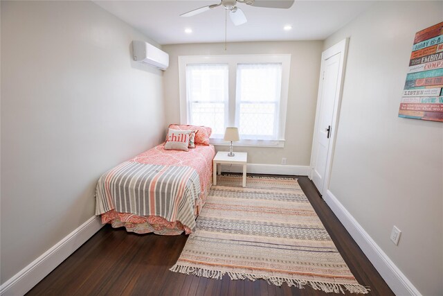 bedroom featuring a wall unit AC, wood finished floors, baseboards, recessed lighting, and ceiling fan