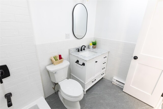 bathroom featuring a baseboard heating unit, toilet, tile walls, vanity, and a wainscoted wall