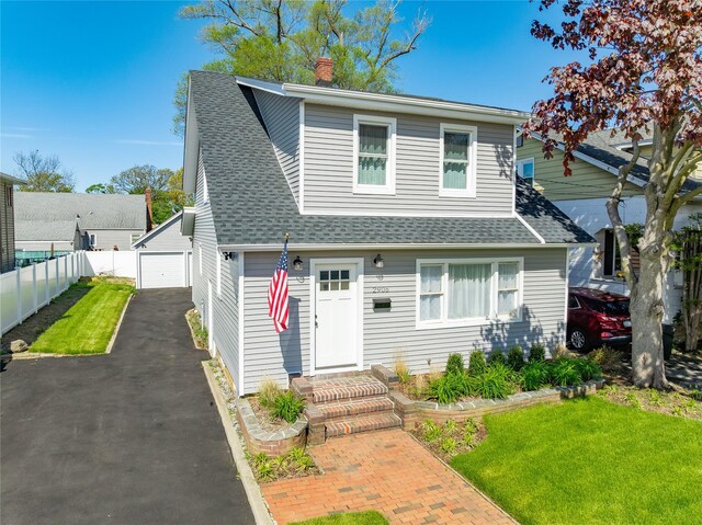 view of front of property featuring a garage, a chimney, a shingled roof, and an outbuilding