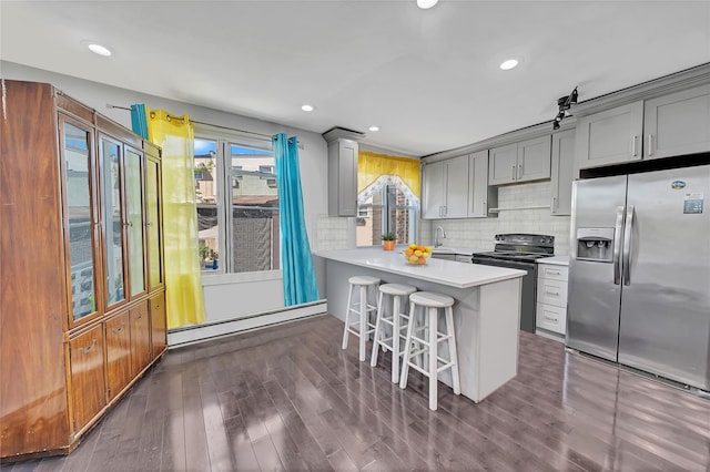 kitchen featuring stainless steel refrigerator with ice dispenser, black / electric stove, gray cabinetry, baseboard heating, and a kitchen bar