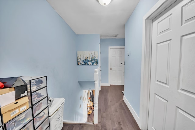 corridor featuring dark wood-type flooring and baseboards