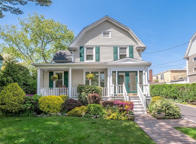 view of front of home with covered porch, a gambrel roof, and a front lawn