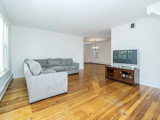 living area featuring a chandelier, light wood-style floors, baseboard heating, and baseboards