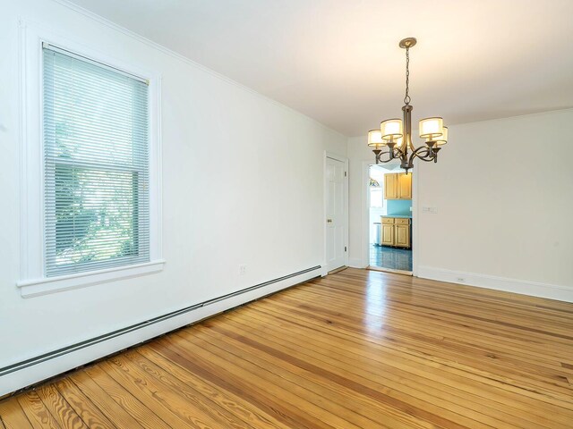 unfurnished dining area with a baseboard heating unit, a chandelier, light wood finished floors, baseboards, and ornamental molding