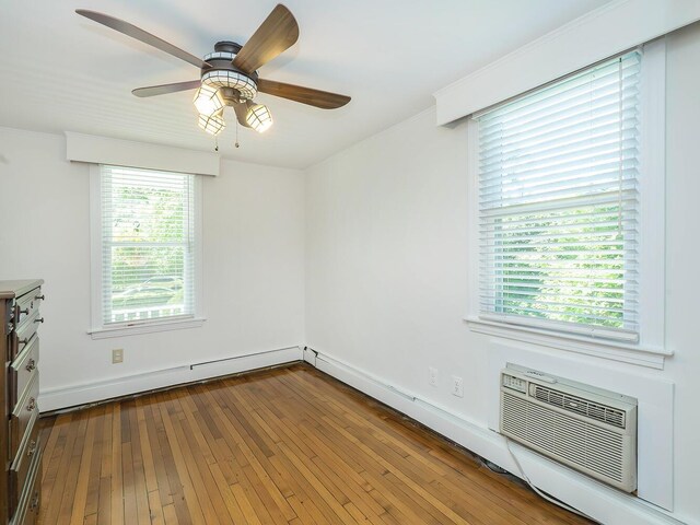 spare room with a ceiling fan, a wall mounted AC, wood-type flooring, baseboard heating, and baseboards