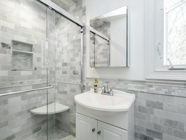 full bath featuring a stall shower, vanity, and tile walls