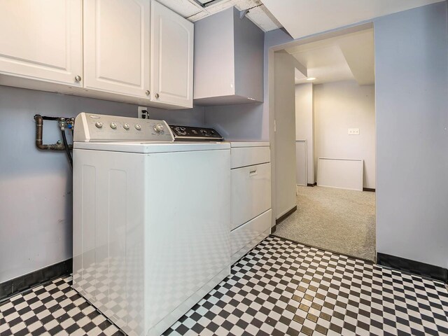 laundry room featuring tile patterned floors, separate washer and dryer, cabinet space, and baseboards