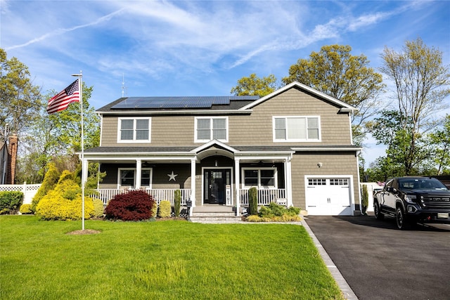 view of front of home with covered porch, solar panels, an attached garage, and asphalt driveway