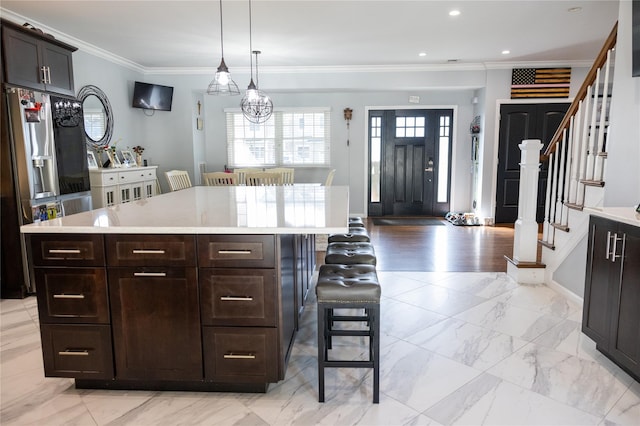 kitchen with a kitchen breakfast bar, light countertops, crown molding, stainless steel refrigerator with ice dispenser, and a kitchen island