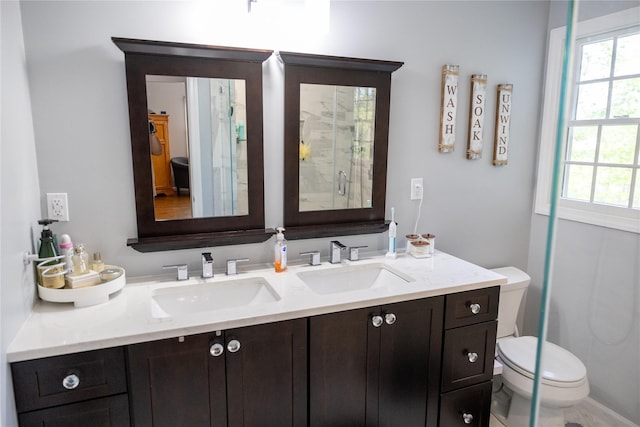 bathroom featuring toilet, healthy amount of natural light, and double vanity