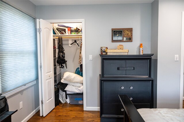 bedroom with dark wood-style floors, baseboards, a walk in closet, and a closet