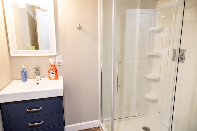 bathroom with a stall shower, vanity, and baseboards