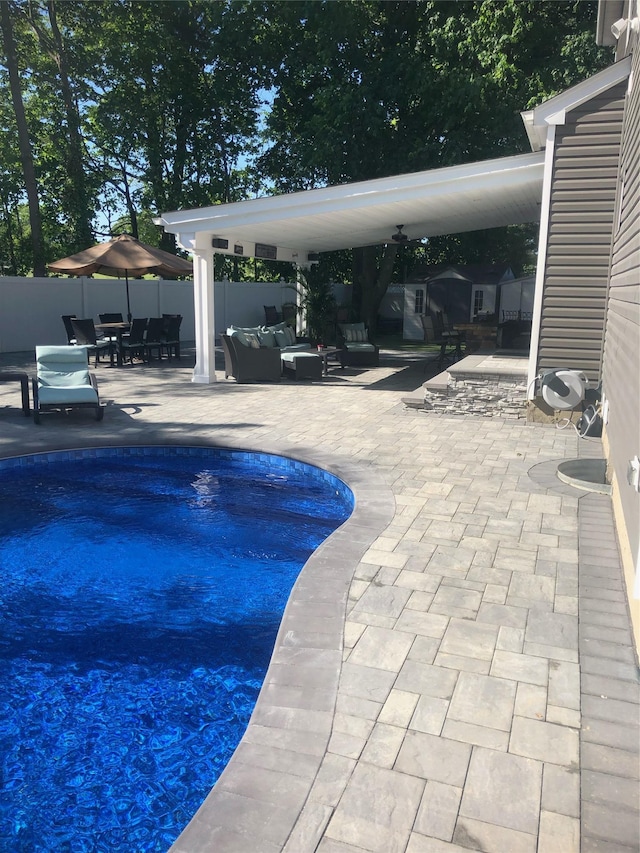 view of pool with an outdoor living space, a patio, and fence