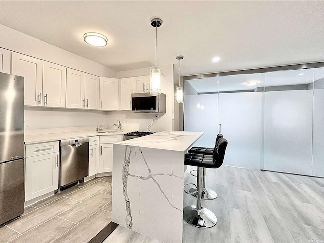 kitchen featuring appliances with stainless steel finishes, light wood-style floors, a kitchen bar, and a sink