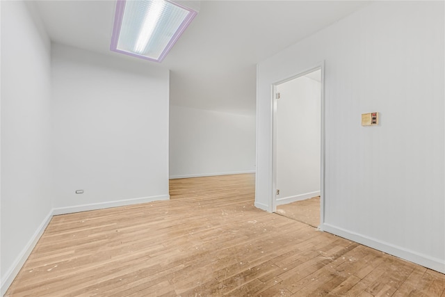 spare room featuring hardwood / wood-style flooring and baseboards