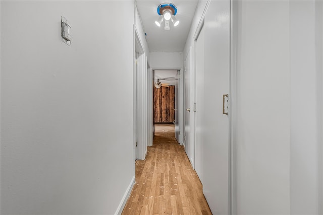 corridor featuring light wood finished floors and baseboards
