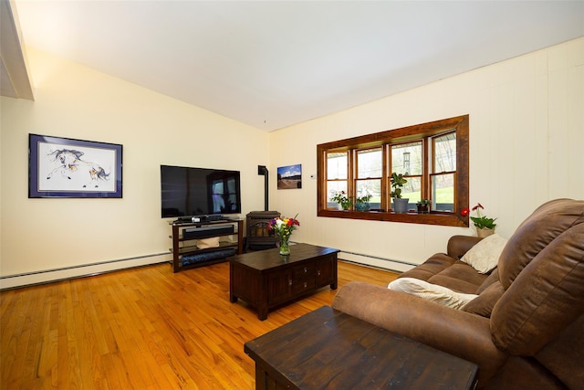 living area with a baseboard heating unit, light wood finished floors, and vaulted ceiling