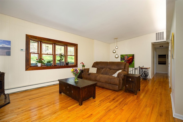 living room with a baseboard heating unit, a wood stove, light wood-style floors, and lofted ceiling