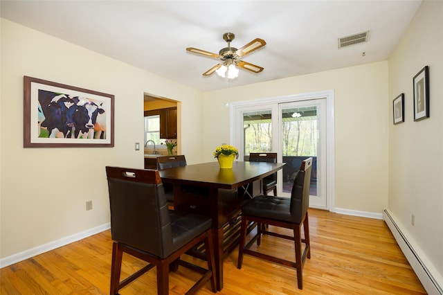dining space with a baseboard radiator, light wood-type flooring, a ceiling fan, and baseboards