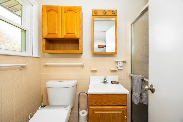 full bath featuring tile walls, toilet, vanity, and a shower with door