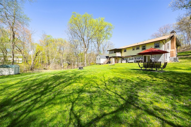 view of green lawn with a storage unit and an outdoor structure