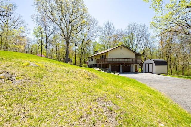 view of front of home with a storage shed, gravel driveway, an outdoor structure, a front yard, and an attached garage