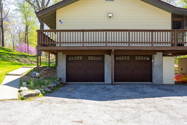 view of side of home with a garage, driveway, a deck, and stucco siding