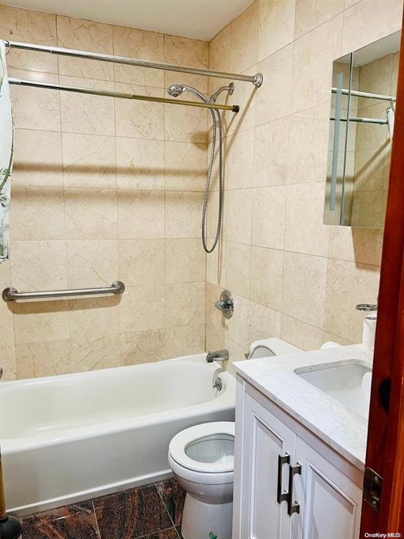 bathroom with tile walls, tub / shower combination, toilet, and vanity