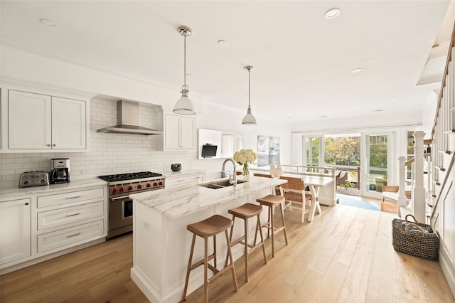 67 Old Boathouse Ln N, Hampton Bays, NY 11946 - kitchen with wall chimney range hood, high end range, a sink, light wood-style flooring, and tasteful backsplash