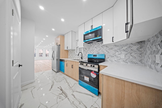 kitchen featuring appliances with stainless steel finishes, a sink, light marble finish floors, light countertops, and recessed lighting