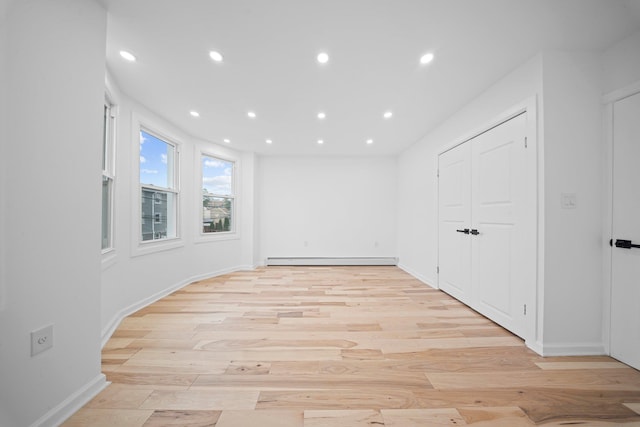 unfurnished room with a baseboard heating unit, recessed lighting, light wood-style flooring, and baseboards
