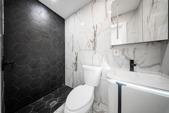 full bath featuring tile walls, a tile shower, vanity, and toilet