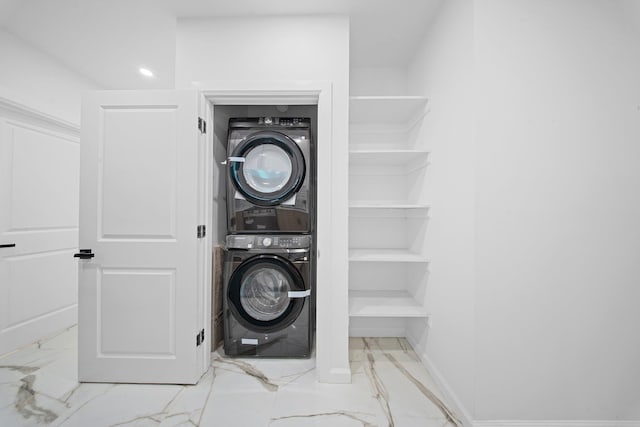 laundry room with stacked washer / drying machine, marble finish floors, and baseboards