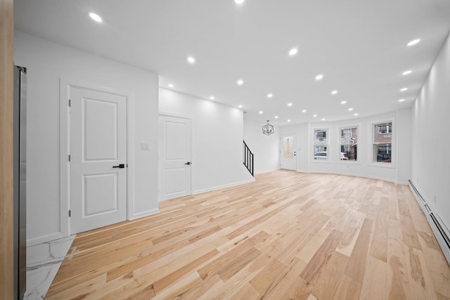 unfurnished living room with a baseboard radiator, light wood-type flooring, stairway, recessed lighting, and baseboards
