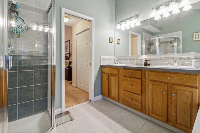 bathroom with a stall shower, double vanity, tile patterned floors, and baseboards