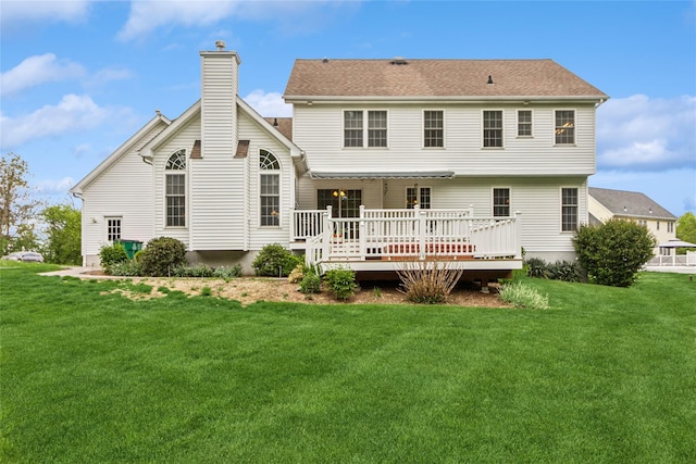 rear view of property with a wooden deck, a lawn, and a chimney