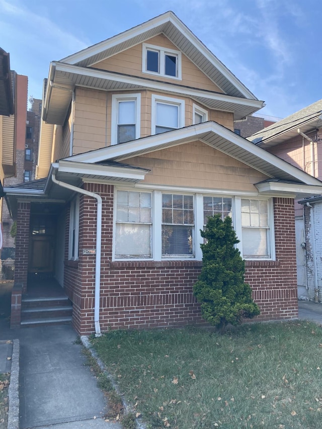 view of front facade with brick siding and a front yard