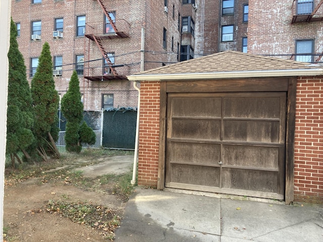 garage featuring fence, driveway, and cooling unit