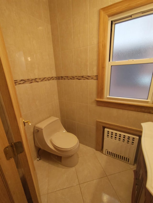 bathroom featuring radiator, toilet, tile patterned flooring, and tile walls