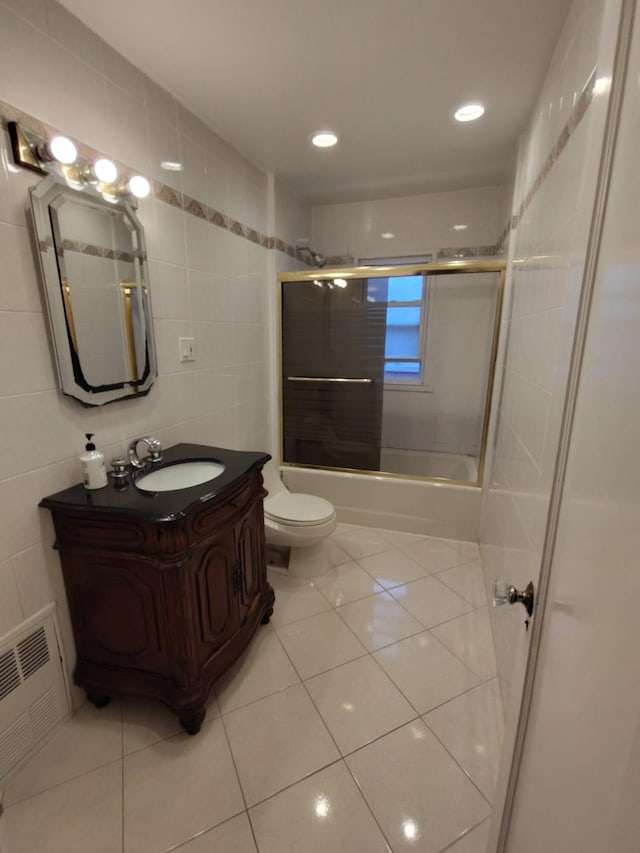 full bathroom featuring tile walls, tile patterned floors, vanity, toilet, and bath / shower combo with glass door
