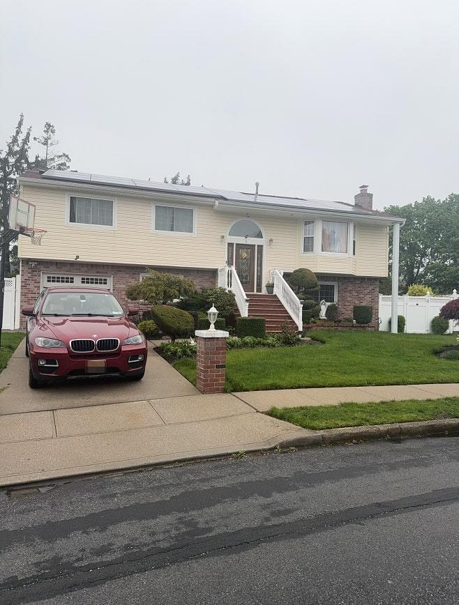 split foyer home with concrete driveway, brick siding, an attached garage, and a chimney