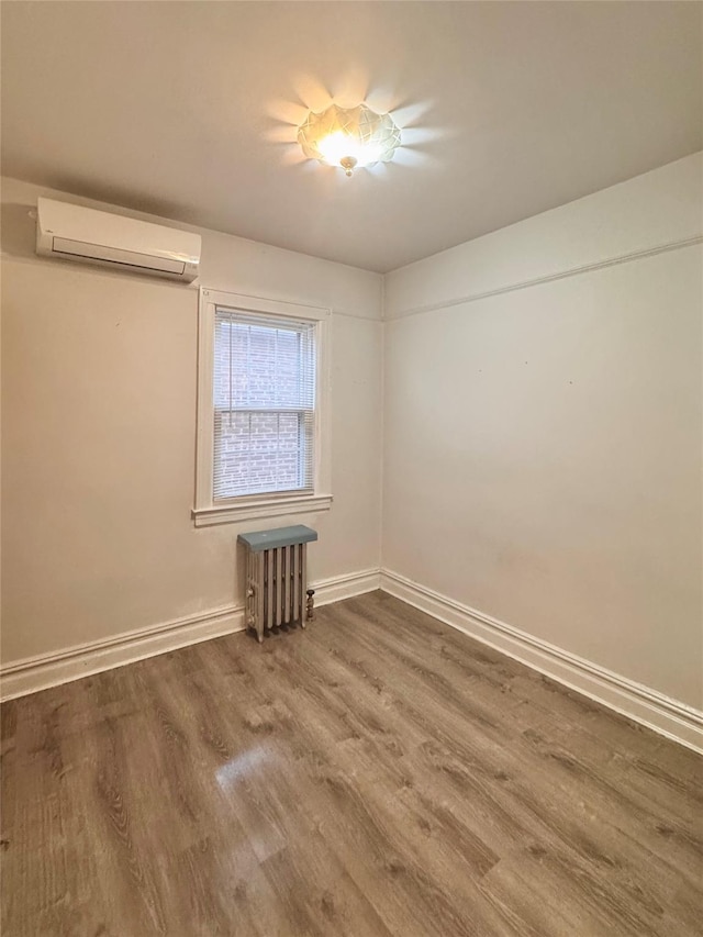 19-11 147th St, Flushing, NY 11357 - unfurnished room with an AC wall unit, radiator, wood finished floors, and baseboards