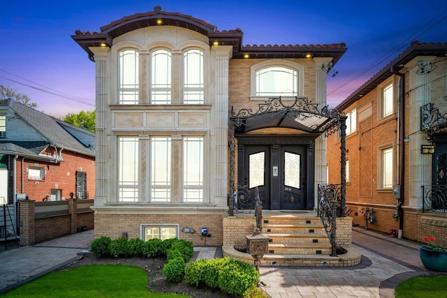 view of front of property featuring french doors, brick siding, and a tiled roof