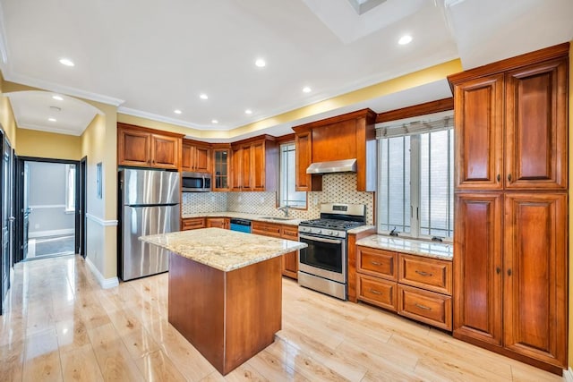 kitchen with stainless steel appliances, ventilation hood, light stone counters, brown cabinets, and decorative backsplash
