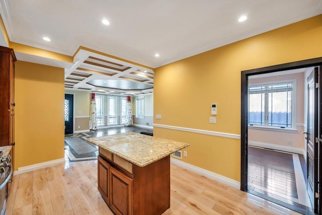 kitchen featuring coffered ceiling, light wood-type flooring, brown cabinets, open floor plan, and baseboards