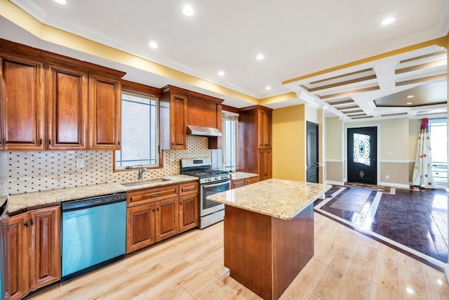 kitchen with stainless steel range with gas cooktop, dishwashing machine, a sink, under cabinet range hood, and a kitchen island