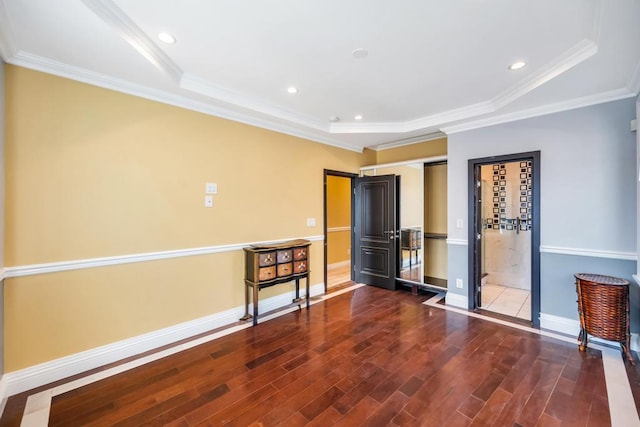 empty room featuring wood finished floors, baseboards, ornamental molding, a raised ceiling, and recessed lighting